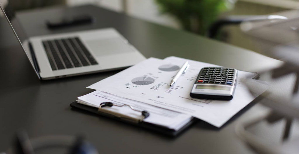 Documents financiers détaillés étalés sur une table : factures d'assurance, relevés HOA et closing costs avec calculatrice